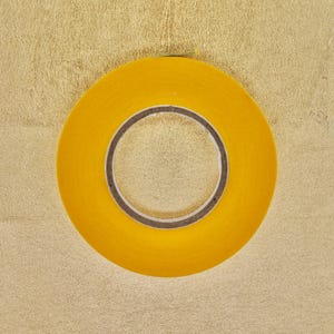 Peut inclure: Un rouleau de ruban adhésif jaune avec un noyau brun. Le ruban est sur un fond doré.