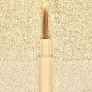 Puede incluir: Primer plano de un cepillo de cerdas naturales con mango de madera. El cepillo está colocado sobre un fondo beige claro.