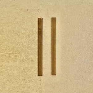 Peut inclure: Deux barres métalliques verticales, fines et de couleur dorée sur un fond beige clair.