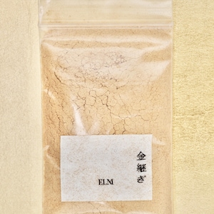 Może przedstawiać: Przezroczysty plastikowy woreczek wypełniony jasnobrązowym proszkiem. Woreczek ma białą etykietę z tekstem "ELM" i japońskimi znakami, które brzmią "金粉".