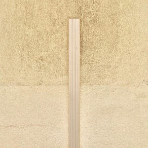 May include: A close-up of a vertical wooden slat against a light beige textured wall.