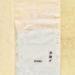 Peut inclure: Un sac en plastique transparent rempli d'une poudre vert clair. Le sac porte une étiquette blanche avec le texte "ROIRO" et des caractères japonais qui se traduisent par "Poudre d'or".