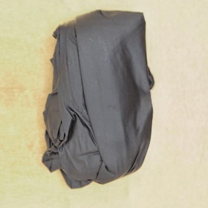 May include: A dark grey fabric bundle folded into a compact shape.