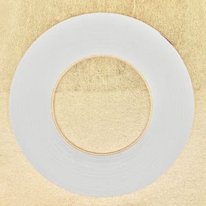 Peut inclure: Un rouleau de ruban adhésif double face blanc sur un fond doré.