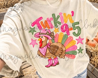 May include: A cream-colored t-shirt featuring a graphic of a turkey wearing a pink cowboy hat with a leopard print band, a pink bandana, and pink cowboy boots. The text reads Turkin' 9-5, surrounded by colorful stars and a fan-shaped tail.