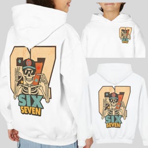 May include: White hoodie featuring a skeleton wearing sunglasses and a baseball cap, with the number 67 and the words "SIX SEVEN" in a vintage style. The design is on the back and front of the hoodie.