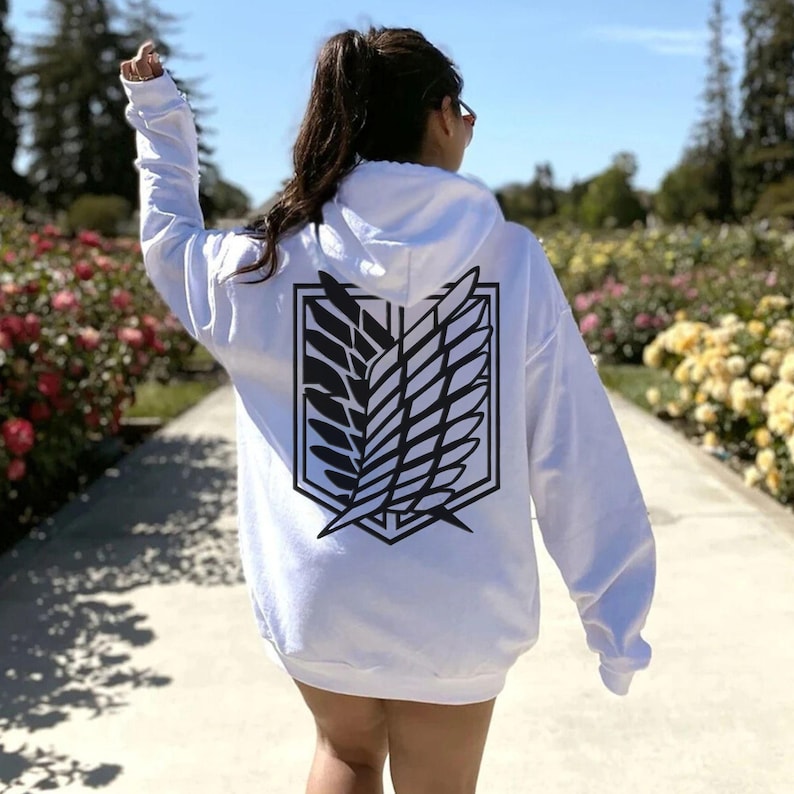 May include: White hoodie with a black and white graphic of the Attack on Titan Wings of Freedom symbol on the back.