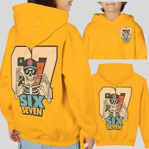May include: Mustard yellow hoodie featuring a skeleton graphic with the text "SIX SEVEN". The design includes a skeleton wearing sunglasses and a baseball cap. The number "67" is prominently displayed.