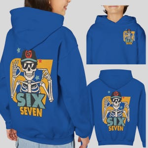 May include: A blue hoodie featuring a skeleton graphic with sunglasses and a baseball cap. The graphic includes the text "SIX SEVEN" and the number "67". The hoodie has a hood and long sleeves.