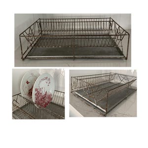 May include: A vintage metal dish rack with a rectangular base and a wire frame. The rack has a distressed, rusty finish and is designed to hold plates and other dishware. The rack is shown with two decorative plates.