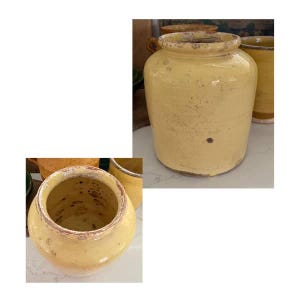 May include: A collection of antique yellow ceramic jars with a distressed finish. The jars have a cylindrical shape with a wide opening and a slightly textured surface. The color is a muted yellow with brown accents.
