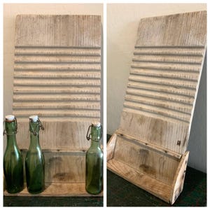 May include: A rustic, wooden washboard with horizontal ridges, paired with three green glass bottles with swing-top closures. The washboard and bottles are displayed on a wooden shelf, creating a vintage aesthetic.