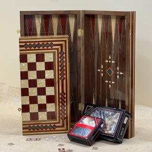 Könnte beinhalten: Ein Backgammon-Set aus Holz mit Schachbrett und Spielsteinen. Das Backgammon-Brett ist dunkelbraun mit eingelegten Designs. Das Schachbrett ist rot und cremefarben. Würfel und Spielsteine sind sichtbar.