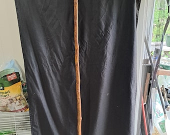 May include: A long, brown walking stick with a natural wood finish. The stick is about 4 feet long and has a smooth, rounded surface.