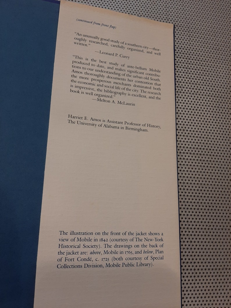Peut inclure: Une couverture de livre avec une illustration en noir et blanc d'une ville. Le titre du livre est "Mobile: The New South City, 1815-1865" et l'auteur est Harriet E. Amos. La couverture du livre comprend &eacute;galement des citations de Leonard P. Curry et Melton A. McLaurin.