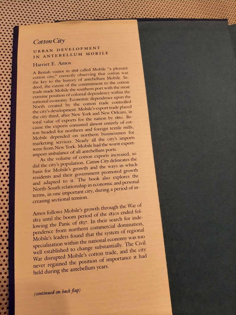 Peut inclure: Une page d'un livre intitul&eacute; "Cotton City: Urban Development in Antebellum Mobile" par Harriet E. Amos. Le texte traite de l'importance du coton pour l'&eacute;conomie de la ville et de sa d&eacute;pendance envers le Nord pour le commerce.