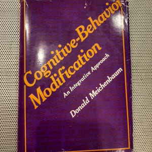 May include: A purple book with the title "Cognitive-Behavior Modification: An Integrative Approach" by Donald Meichenbaum.