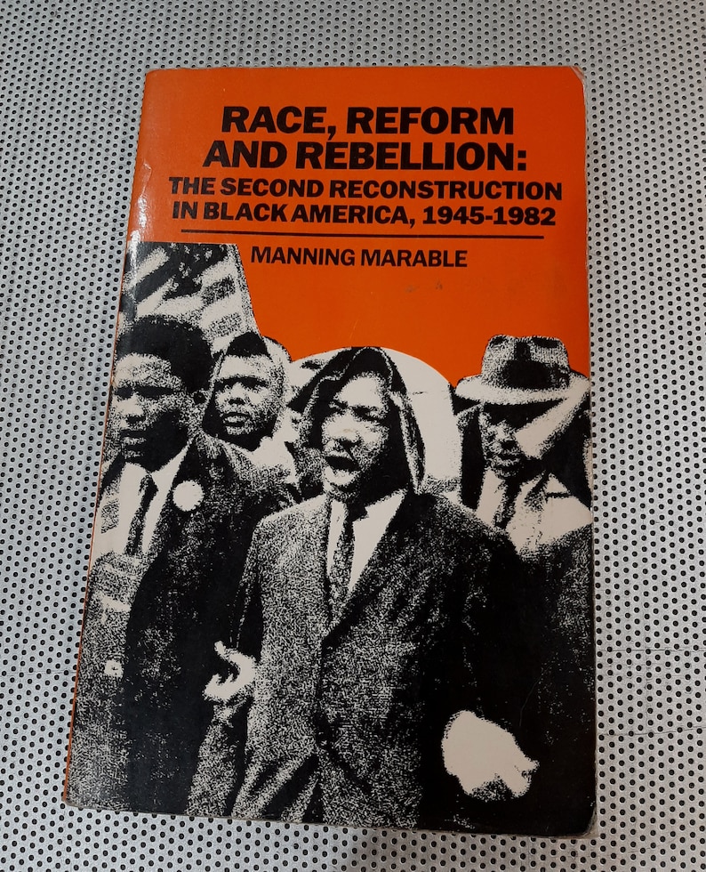 Op de afbeelding: Een boekomslag met een zwart-witfoto van een groep mensen. De titel van het boek is "Race, Reform and Rebellion: The Second Reconstruction in Black America, 1945-1982" door Manning Marable.
