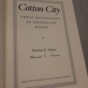 Peut inclure: Un livre intitul&eacute; "Cotton City : Urban Development in Antebellum Mobile" par Harriet E. Amos. La couverture du livre pr&eacute;sente une bordure d&eacute;corative et le logo de l'University of Alabama Press.