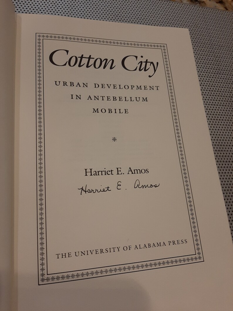 Peut inclure: Un livre intitul&eacute; "Cotton City : Urban Development in Antebellum Mobile" par Harriet E. Amos. La couverture du livre pr&eacute;sente une bordure d&eacute;corative et le logo de l'University of Alabama Press.