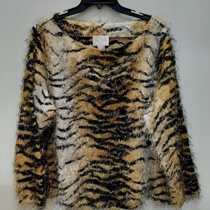 May include: A long-sleeved, fuzzy sweater with a tiger stripe pattern in black, white, and brown.
