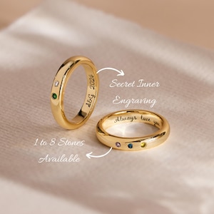 May include: Two gold rings featuring small embedded gemstones and interior engravings. One ring displays the text A&G 2026, while the other shows the text Always love you. The image includes the text Secret Inner Engraving and 1 to 8 Stones Available.