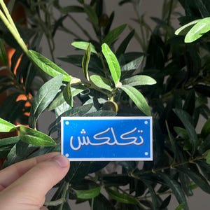 May include: A blue sticker with white Arabic text that reads "Thank you" on a green plant background.