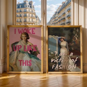 May include: Two framed artworks with gold ornate frames. One features a woman in a white dress with the text "I WOKE UP LIKE THIS" in pink. The other shows a woman in a white dress with the text "I am a victim of FASHION".