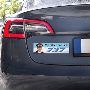 May include: A blue car's rear with a bumper sticker that reads "My other car is a 737." The sticker features a pilot in uniform against a sky background. The car has red taillights.