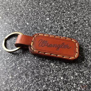 May include: Brown leather keychain with a gold metal ring and the word "Wrangler" embossed in gold lettering.