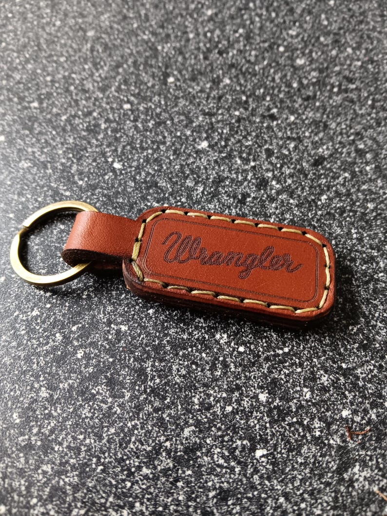 May include: Brown leather keychain with a gold metal ring and the word "Wrangler" embossed in gold lettering.