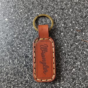 May include: Brown leather keychain with a metal ring and the word "Wrangler" embossed on the front.