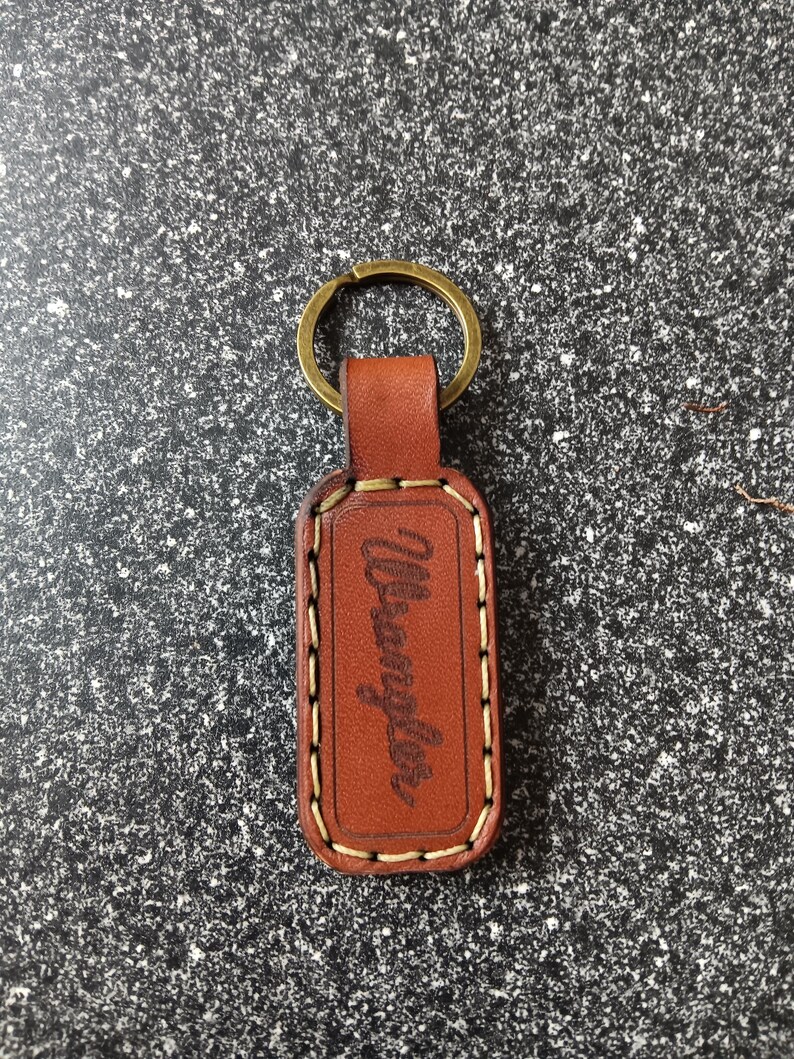May include: Brown leather keychain with a metal ring and the word "Wrangler" embossed on the front.
