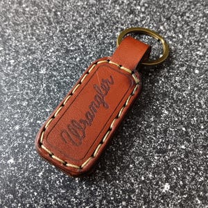 May include: Brown leather keychain with white stitching and the word "Urban" embossed on it.