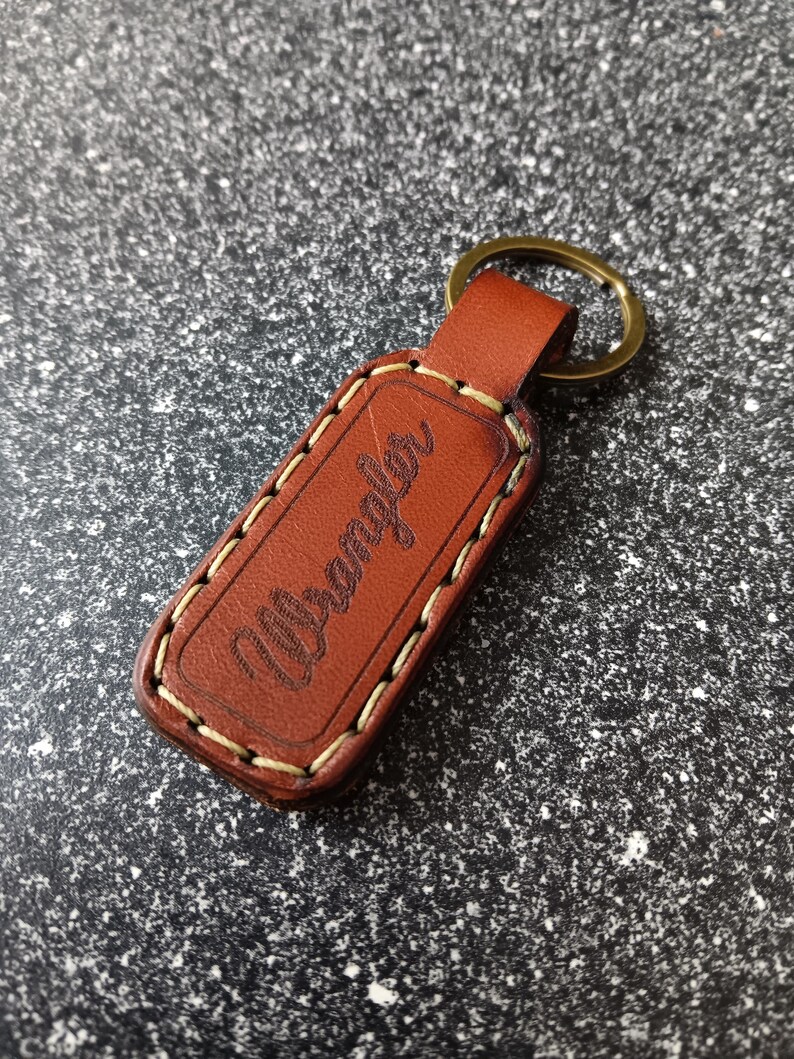 May include: Brown leather keychain with white stitching and the word "Urban" embossed on it.