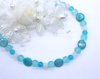 May include: A blue and white beaded necklace with iridescent accents. The necklace is made of frosted glass beads and iridescent shell beads.