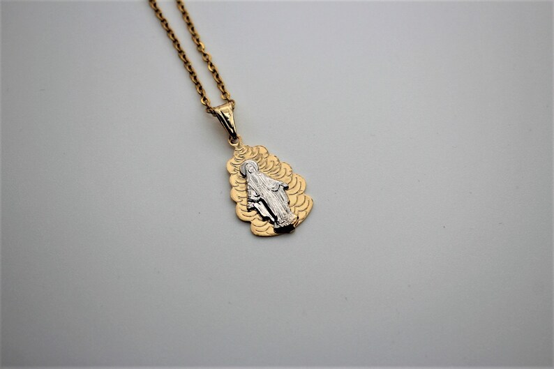 K&ouml;nnte beinhalten: Goldkette mit einem Anh&auml;nger, der ein zweifarbiges Bild der Jungfrau Maria zeigt.