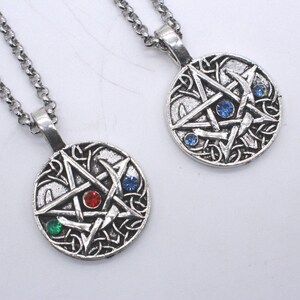 May include: Two silver-toned circular pendants on matching link chains. Each pendant features an embossed pentagram design with intricate knotwork detailing. One pendant is accented with a red and a green gemstone, while the other has two blue gemstones.