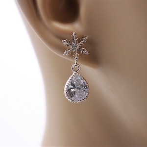 May include: Silver snowflake dangle earrings with a teardrop-shaped clear crystal.