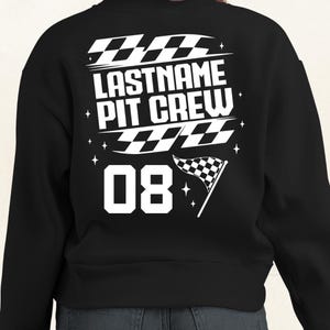 May include: Black sweatshirt with white text and graphics. The text reads "LASTNAME PIT CREW" above the number "08". The design includes checkered flags and star accents, creating a racing theme.
