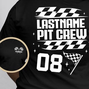 May include: Black t-shirt with a white graphic that reads "LASTNAME PIT CREW" above the number "08". The design includes checkered flag elements and stars. A smaller circular graphic on the sleeve shows two checkered flags and text.