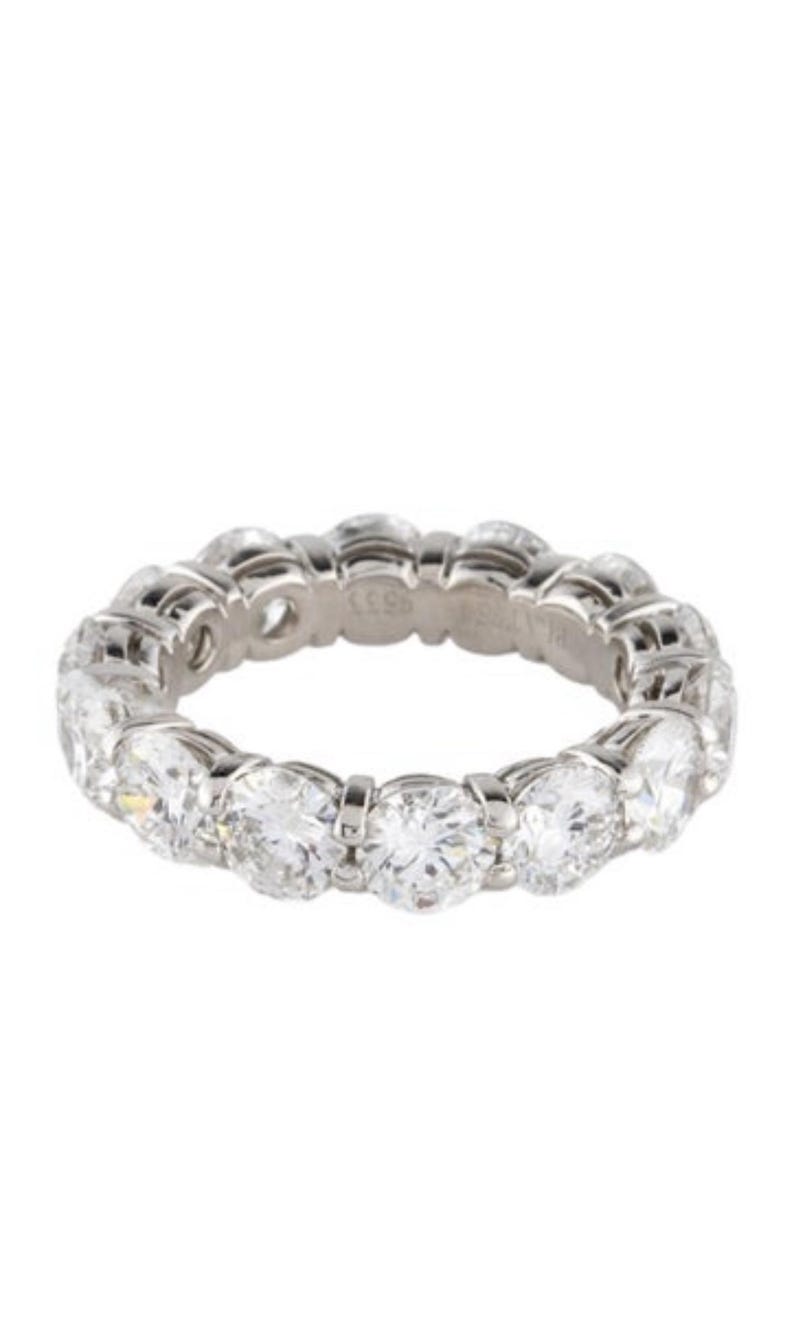 May include: A platinum eternity band featuring a row of round brilliant cut diamonds.