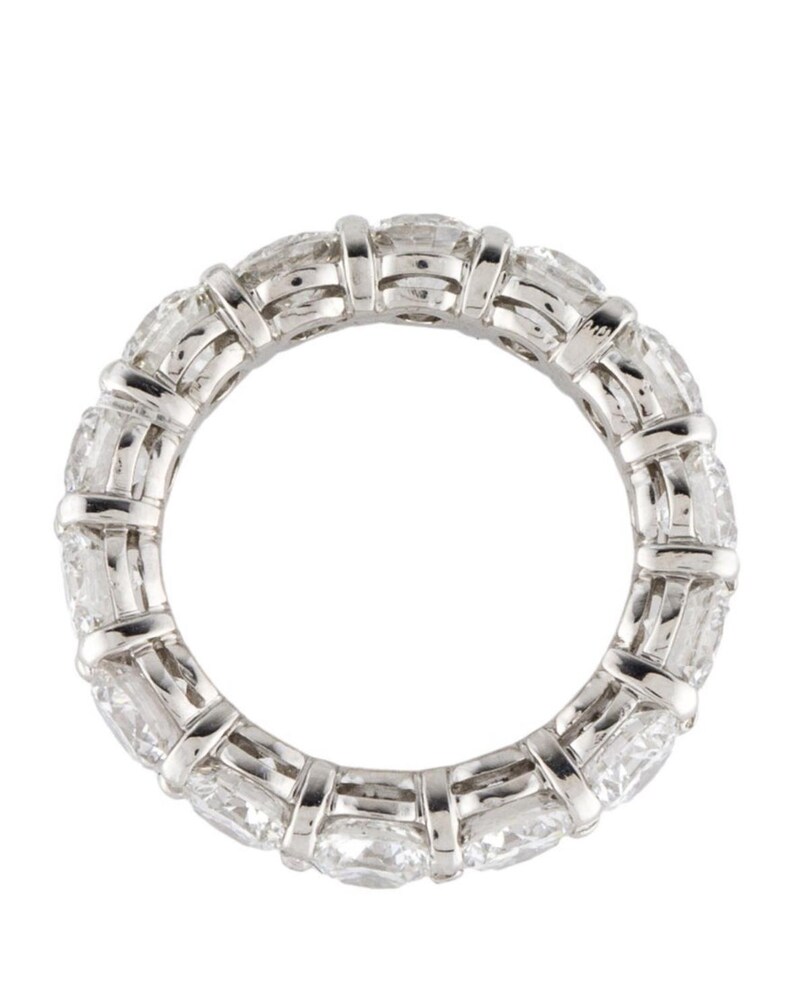 May include: A platinum eternity band featuring a row of round brilliant diamonds set in a pave setting.