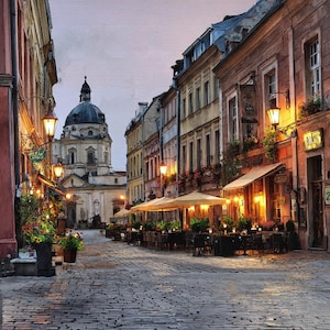 May include: A cobblestone street in a European city at dusk, lined with buildings, restaurants, and street lamps. A large domed building is visible in the distance. The scene is illuminated by warm light.