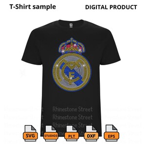 May include: A black t-shirt featuring a rhinestone design of the Real Madrid football team logo. The logo depicts a white and blue crest with a gold crown on top. The design is surrounded by rhinestones in various colours, including gold, silver, blue, and red.