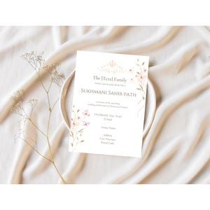 May include: A white invitation card with a floral design and the text "The [Text] Family invites you to join them for a Sukhmani Sahib Path in honor of the upcoming wedding celebration of [Name] and [Name]. The date, time, venue name, address, city, province, and postal code are listed below the text."