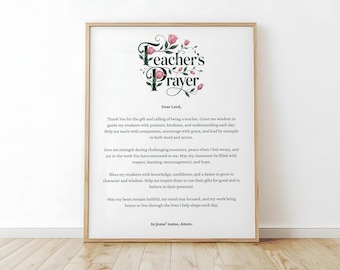 May include: A framed print with the text "Teacher's Prayer" in a decorative font, adorned with floral accents. The prayer is printed in black on a white background, encased in a light brown wooden frame. The print is displayed on a light-colored wooden floor.