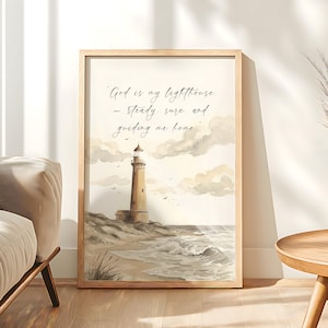 May include: A framed watercolor print featuring a lighthouse on a sandy shore under a cloudy sky. The lighthouse is beige with a white top. The print includes the text: "God is my lighthouse - steady, sure, and guiding me home."