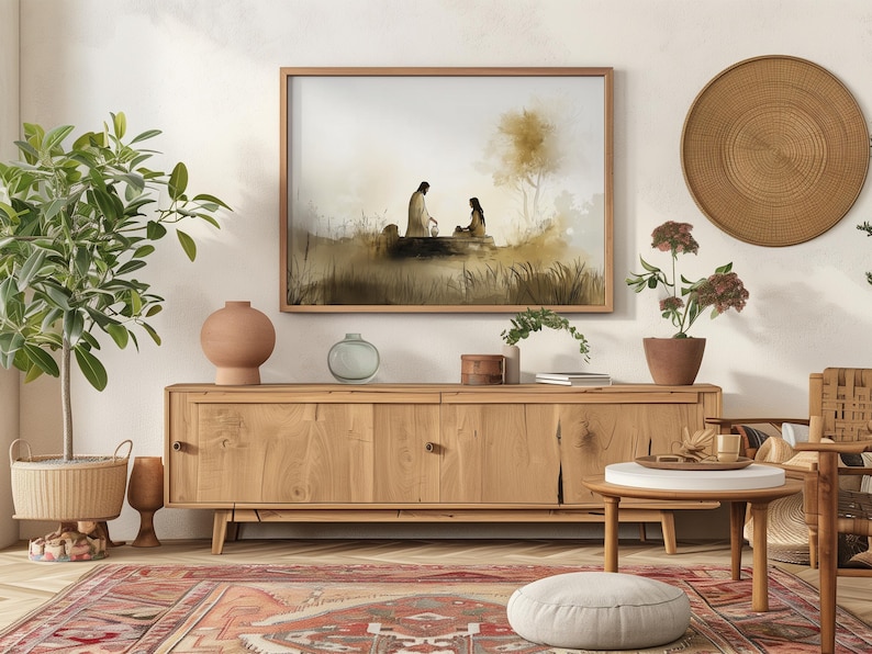 May include: A watercolor painting of two figures sitting by a well, framed in a wooden frame and hanging on a white wall above a wooden cabinet. The painting is set against a light brown background with a tree in the background.