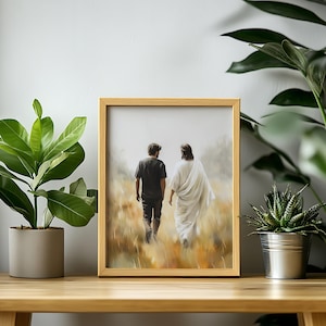 May include: A framed painting of two figures walking away from the viewer in a field. The figure on the left is wearing a black shirt and jeans, while the figure on the right is wearing a white robe. The painting is set against a light brown background.
